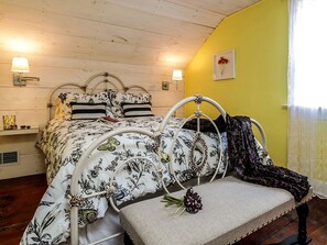 A bed with a floral bedspread, a bench with a blanket, and two wall-mounted lamps. - Elegant Farm Cottage Rental for a Countryside Getaway near Lancaster, Pennsylvania (Columbia)