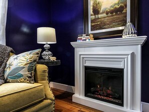 A living room with a fireplace, a sofa, a lamp, and a bookshelf. - Elegant Farm Cottage Rental for a Countryside Getaway near Lancaster, Pennsylvania (Columbia)