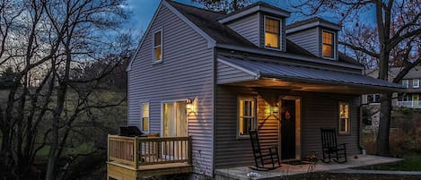 A two-story house with a porch, a deck, and a small garden area.