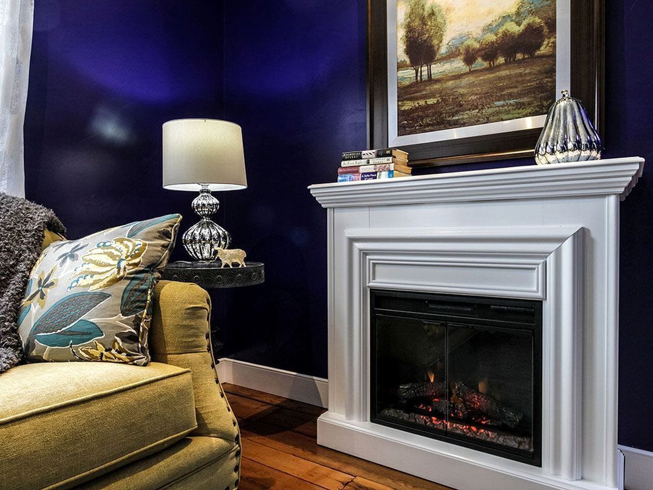 A living room with a fireplace, a sofa, a lamp, and a bookshelf.