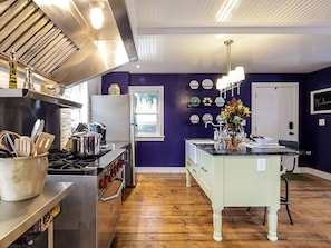 A kitchen with a stove, refrigerator, and a dining area with a table and chairs. - Elegant Farm Cottage Rental for a Countryside Getaway near Lancaster, Pennsylvania (Columbia)