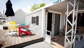 A covered outdoor area with a table and chairs, a door leading to a room, and a sign that reads 'PORT'.