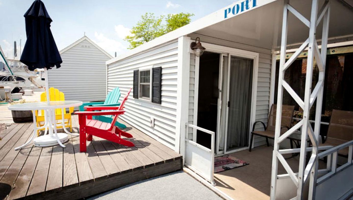 Un espacio al aire libre cubierto con una mesa y sillas, una puerta que da a una habitación y un letrero que dice 'PORT'.