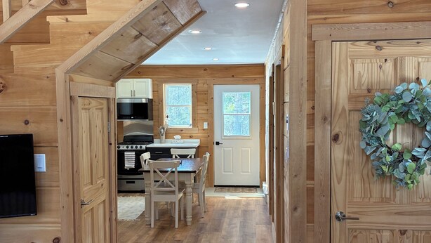 A wooden interior with a staircase, a dining area, and a kitchen.