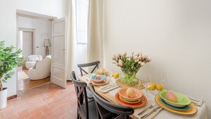 A dining area with a table set for four, a vase of flowers, and a view into another room. - The Gallo Promenade in Lucca (Lucca)