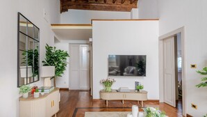 A hallway with a wooden floor, a mirror, a TV, and a plant. - The Gallo Promenade in Lucca (Lucca)