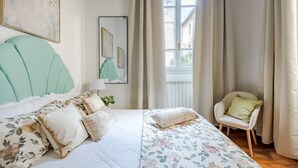 A bedroom with a bed, a chair, a window, and artwork on the walls. - The Gallo Promenade in Lucca (Lucca)