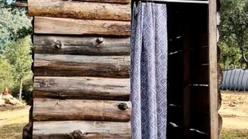 A log cabin with a patterned curtain, a visible door, and a natural outdoor setting.