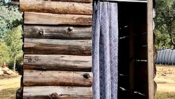 Una cabaña de troncos con un cortinero estampado, una puerta visible y un entorno natural.