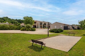 A courtyard with a paved area, a bench, and a building with multiple balconies. - Apartment 'Résidence Château Saint Martin' with Balcony, Wi-Fi and Air Conditioning (Saint-Martin-d'Ardèche)