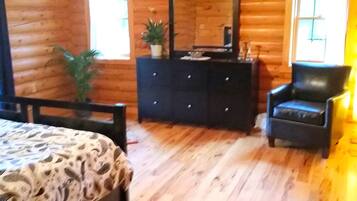 L’intérieur d’un chalet en bois, avec un lit, une commode, une chaise et un grand miroir.
