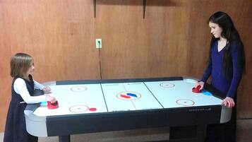 Deux personnes jouent au palet sur une table, avec un mur en bois en arrière-plan.