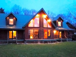 A log cabin with a large central window, multiple smaller windows, and a porch.