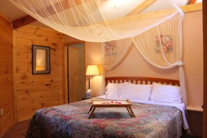 Una stanza in legno con un letto, un comodino, una lampada e una tenda a baldacchino.