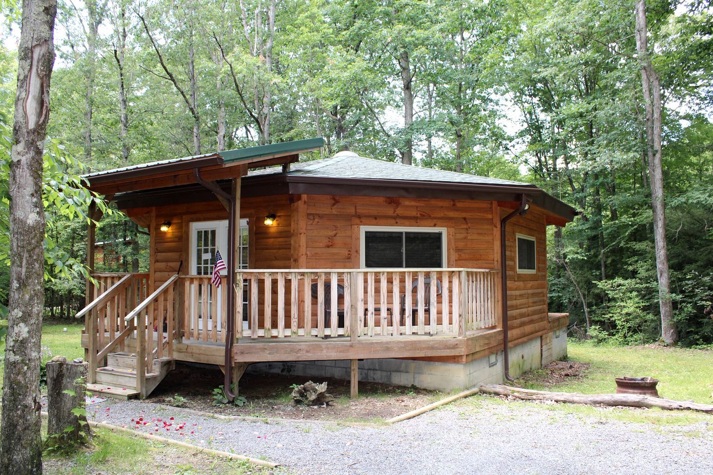 Une cabane en bois avec une véranda, une petite terrasse et un drapeau.