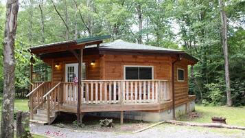 Eine Holzhütte mit Veranda, einer kleinen Terrasse und einer Flagge.