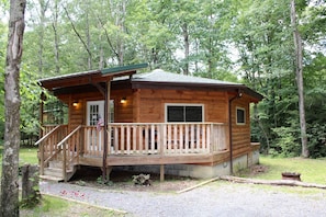 Een houten chalet met een veranda, een klein terras en een vlag.