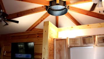 A wooden ceiling with exposed beams, a ceiling fan, and a mounted television.