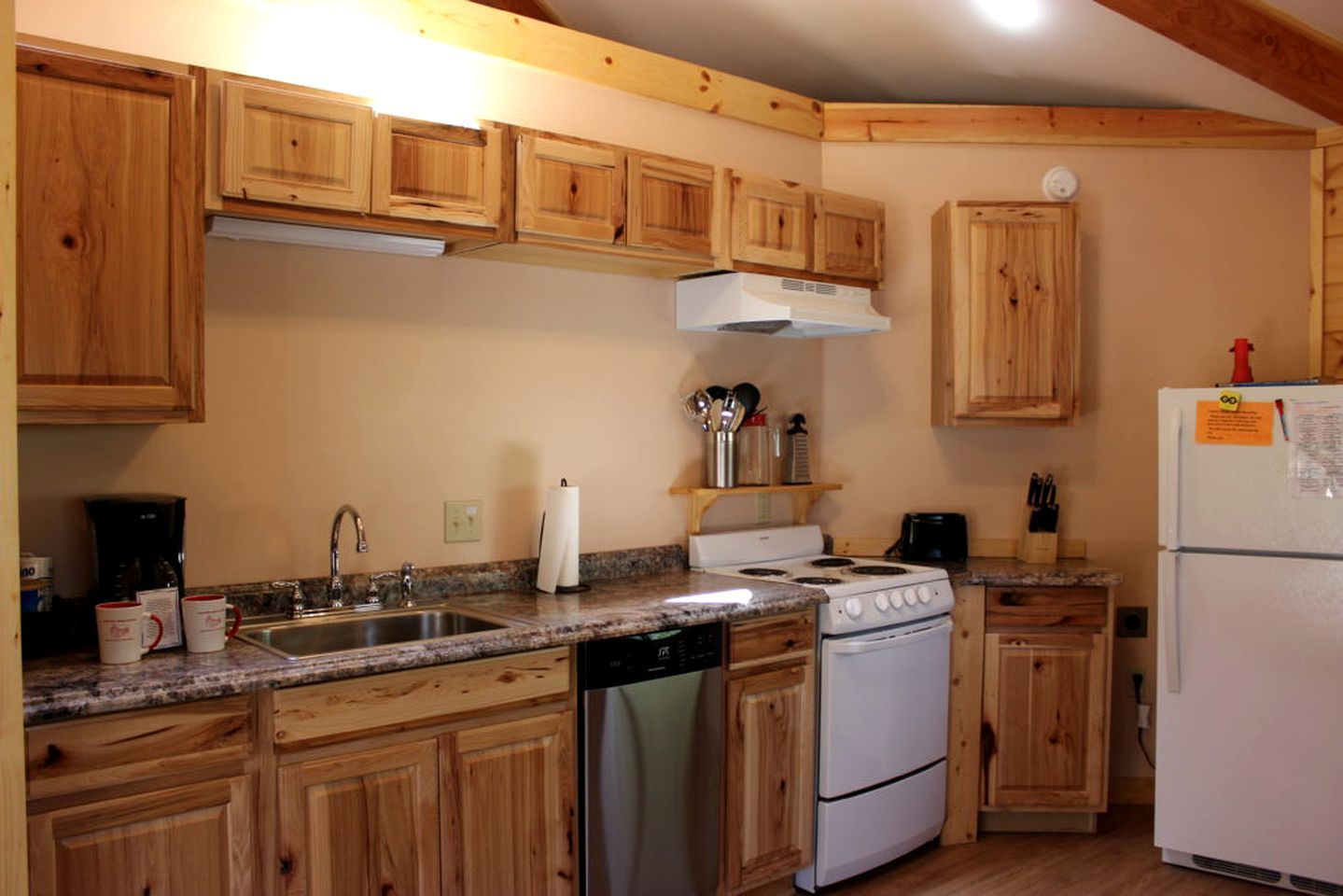 A kitchen with wooden cabinets, a stove, a dishwasher, and a refrigerator.
