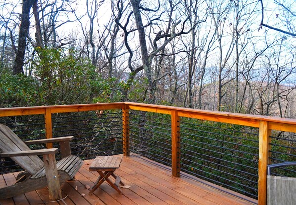 A wooden deck with a metal railing, a wooden chair, and a small table.