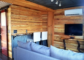 Een gezellig interieur van een blokhut met een houten wand, een bank, een televisie en een airconditioning.