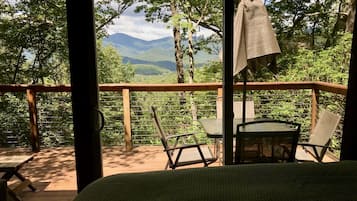 A wooden deck with a bed, two chairs, and a table.