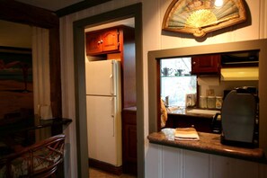 A compact kitchen with a refrigerator, a sink, and a coffee maker.