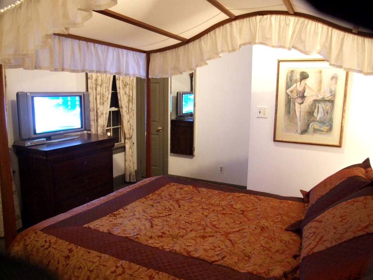 Un dormitorio con cama, cómoda, televisor y un cuadro en la pared.
