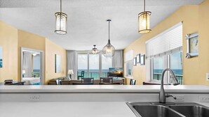 Een moderne keuken met een groot schiereiland, een eetgedeelte met uitzicht en een balkon met uitzicht.