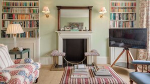 Una sala de estar con chimenea, estanterías, televisor y muebles con diseños.