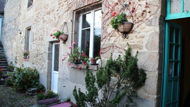 Un edificio de piedra con escaleras, plantas en macetas y una puerta.