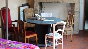 Una habitación rústica con chimenea de piedra, una mesa redonda con sillas, un candelabro y una cama con edredón floral.