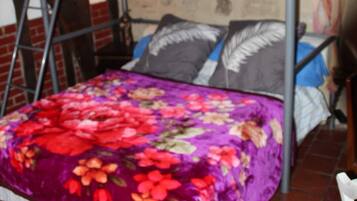 Una cama litera con cubrecama floral, una escalera y una pared con diseño de ladrillo.
