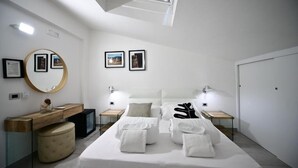 A modern hotel room with a large bed, two bedside tables, a round mirror, and framed pictures on the wall. - Royal Rooms (Laura)