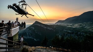 A cable car system with passengers, overlooking a mountainous landscape during sunset. - Royal Rooms (Laura)