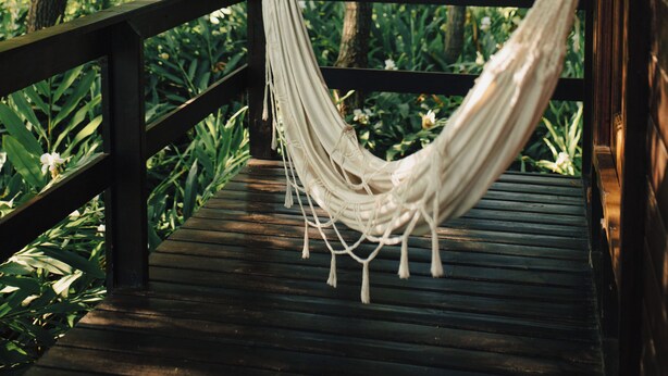 A hammock on a wooden deck with a view of trees. - Cabaña Los Juncos (Tigre)
