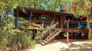 A wooden cabin with a deck, a staircase, and a covered seating area. - Cabaña Los Juncos (Tigre)