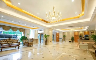 Eine Hotelhalle mit einer Kronleuchter, Sofas, einer Rezeption und Zimmerpflanzen.