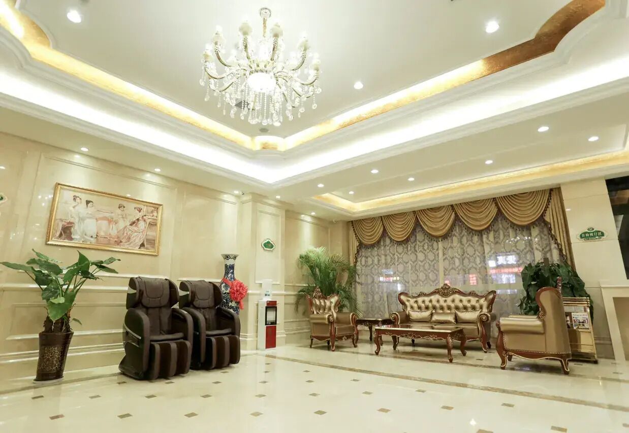 A spacious lobby with a chandelier, seating area, and a large window with curtains.