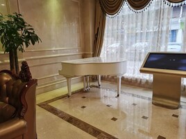 Egy nagyméretű zongora, egy modern konzolasztal és egy kényelmes, puha karosszék egy jól megvilágított szobában, márványburkolattal.