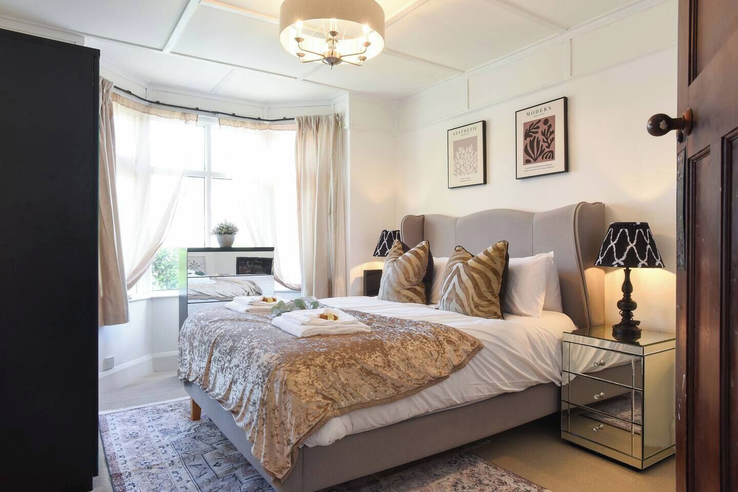A bedroom with a bed, bedside tables, a lamp, and a window with curtains.