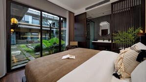 A modern hotel room with a large bed, a bathroom, and a view of a traditional building.