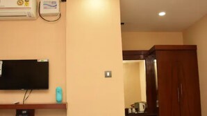 A room with a flat-screen TV mounted on the wall, a small refrigerator, and a wooden wardrobe. - Hotel Shar Inn (Balrampur)