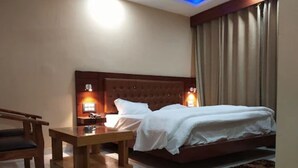 A hotel room with a bed, bedside tables, a chair, and a small table. - Hotel Shar Inn (Balrampur)