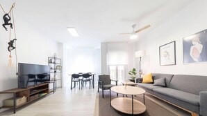 Un salon moderne comprenant un canapé, une table basse, un téléviseur et un coin repas.