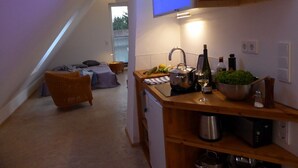 Una cocina compacta con televisor, cafetera y diversos electrodomésticos.