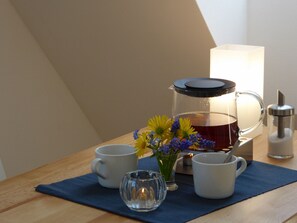A table with a coffee pot, two cups, a glass, and a vase with flowers. - Apartment 'Max' with Shared Garden and Wi-Fi (Kassel)
