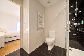 A modern bathroom with a toilet, shower, and a glass door leading to a bedroom. - Family Retreat with Views, Terrace & Parking (Vitoria-Gasteiz)