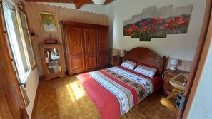 Une chambre à coucher avec un lit en bois, une table de chevet, une commode et un tableau accroché au mur.