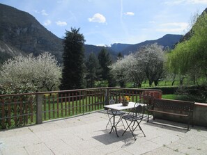 Une terrasse avec une table et des chaises, une clôture en bois et une vue sur les montagnes et les arbres.